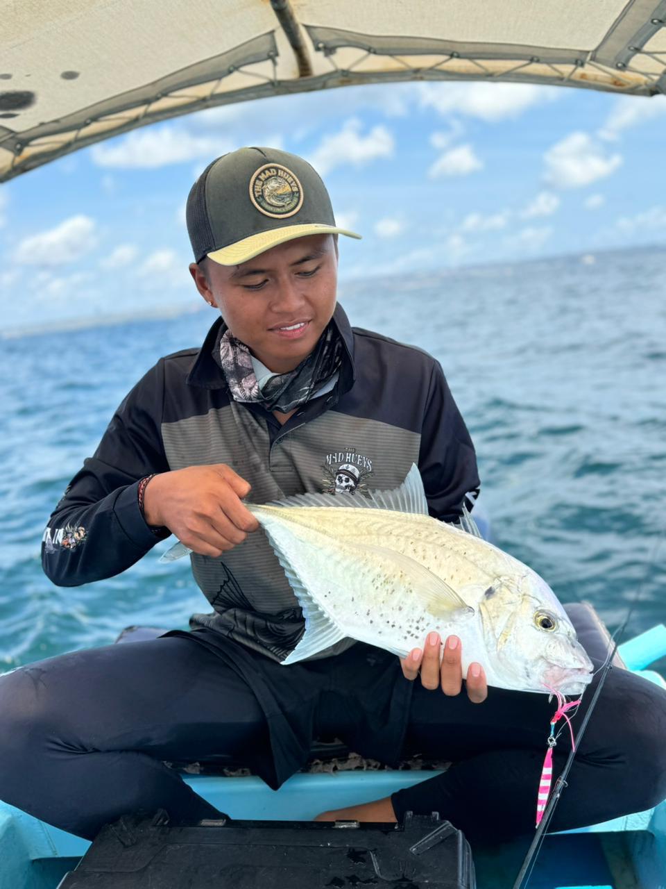 Guest proudly holding a large trevally on the boat